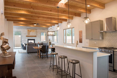 Inspiration for a southwestern gray floor open concept kitchen remodel in Albuquerque with shaker cabinets, gray cabinets, white backsplash, glass tile backsplash, stainless steel appliances, an island and white countertops