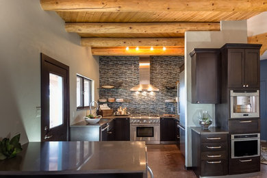 Example of a mid-sized trendy u-shaped eat-in kitchen design in Albuquerque with shaker cabinets, dark wood cabinets, granite countertops, multicolored backsplash, matchstick tile backsplash, stainless steel appliances, a peninsula and a farmhouse sink