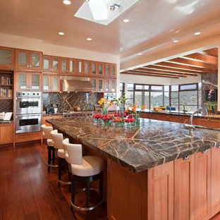 Large southwestern open concept kitchen ideas - Inspiration for a large southwestern u-shaped medium tone wood floor and brown floor open concept kitchen remodel in Albuquerque with an undermount sink, glass-front cabinets, medium tone wood cabinets, multicolored backsplash, stainless steel appliances, an island, granite countertops and stone slab backsplash