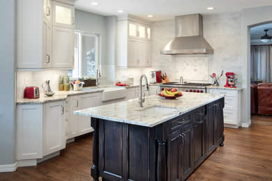 Inspiration for a large transitional l-shaped medium tone wood floor and brown floor eat-in kitchen remodel in Albuquerque with a farmhouse sink, shaker cabinets, white cabinets, granite countertops, gray backsplash, ceramic backsplash, stainless steel appliances and an island