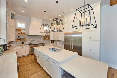 Bild på ett mycket stort vit vitt kök, med en undermonterad diskho, skåp i shakerstil, vita skåp, bänkskiva i kvarts, rostfria vitvaror, en köksö och brunt golv