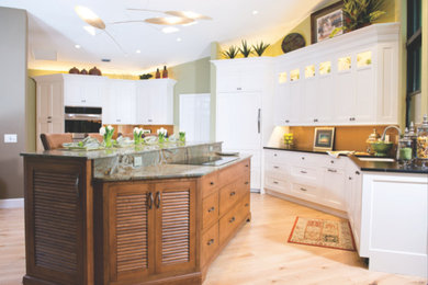 Foto de cocina clásica renovada con fregadero bajoencimera, armarios con paneles empotrados, puertas de armario blancas, suelo de madera clara y una isla