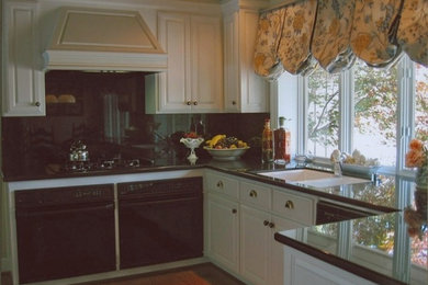 Inspiration for a mid-sized rustic l-shaped medium tone wood floor eat-in kitchen remodel in San Francisco with a double-bowl sink, raised-panel cabinets, white cabinets, granite countertops, black backsplash, stone slab backsplash, black appliances and a peninsula