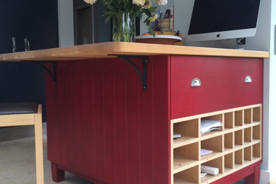 This is an example of a small modern kitchen/diner in Wiltshire with flat-panel cabinets, red cabinets, wood worktops and an island.