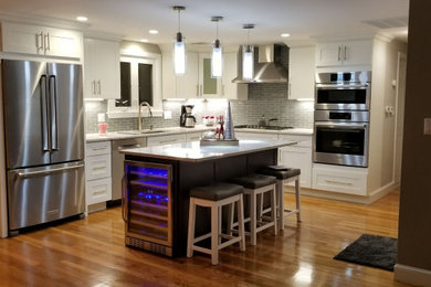 Inspiration for a mid-sized transitional l-shaped dark wood floor and brown floor open concept kitchen remodel in Other with shaker cabinets, white cabinets, gray backsplash, stainless steel appliances, an island, an undermount sink and white countertops