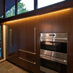 This is an example of a large midcentury galley eat-in kitchen in Cincinnati with a single-bowl sink, flat-panel cabinets, medium wood cabinets, quartz benchtops, stainless steel appliances, porcelain floors and with island.