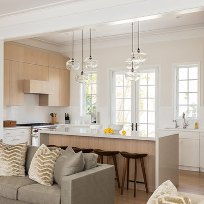 Beach style u-shaped medium tone wood floor open concept kitchen photo in Miami with flat-panel cabinets, light wood cabinets, paneled appliances and an island