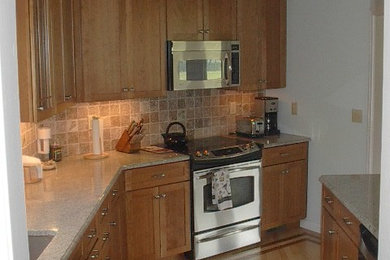 Example of a small classic galley light wood floor enclosed kitchen design in New York with an undermount sink, flat-panel cabinets, medium tone wood cabinets, granite countertops, stone tile backsplash and stainless steel appliances