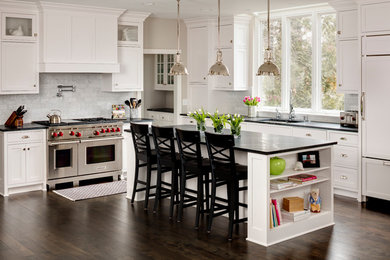 Inspiration for a transitional dark wood floor kitchen remodel in Milwaukee with an undermount sink, shaker cabinets, white cabinets, gray backsplash, stainless steel appliances and an island