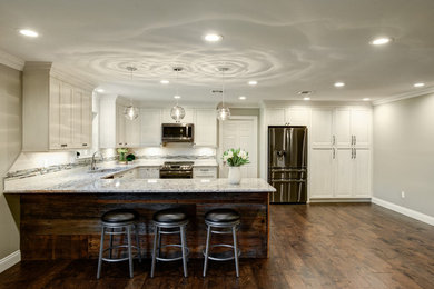 ニューオリンズにある高級な中くらいなトランジショナルスタイルのおしゃれなキッチン (アンダーカウンターシンク、フラットパネル扉のキャビネット、白いキャビネット、クオーツストーンカウンター、白いキッチンパネル、セラミックタイルのキッチンパネル、シルバーの調理設備、濃色無垢フローリング、茶色い床) の写真