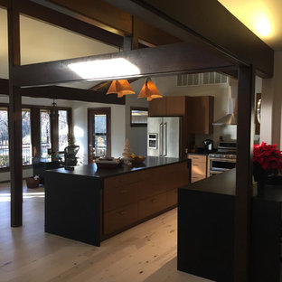 This is an example of a mid-sized midcentury l-shaped open plan kitchen in Other with a double-bowl sink, flat-panel cabinets, medium wood cabinets, quartz benchtops, stainless steel appliances, light hardwood floors, with island, beige floor and black benchtop.