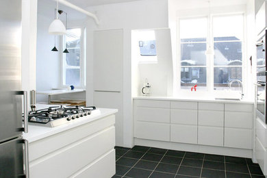 Imagen de cocinas en L contemporánea de tamaño medio con fregadero bajoencimera, puertas de armario blancas, encimera de acrílico, electrodomésticos de acero inoxidable y suelo de pizarra