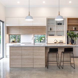 Idee per una cucina parallela design di medie dimensioni con lavello sottopiano, ante lisce, ante in legno chiaro, top in quarzo composito, paraspruzzi bianco, paraspruzzi con piastrelle diamantate, elettrodomestici in acciaio inossidabile, pavimento in cemento, isola, pavimento grigio e top grigio