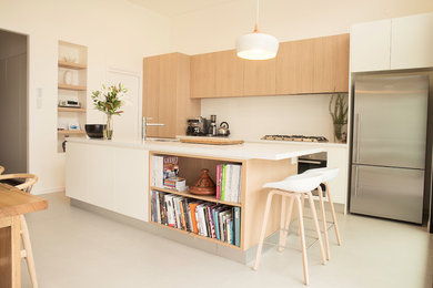 Photo of a medium sized scandi galley open plan kitchen in Melbourne with a submerged sink, flat-panel cabinets, white cabinets, engineered stone countertops, stone slab splashback, stainless steel appliances, porcelain flooring and an island.