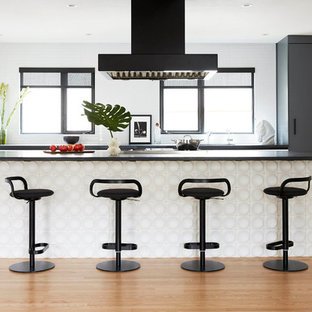 Small scandinavian open concept kitchen pictures - Small danish galley medium tone wood floor open concept kitchen photo in San Francisco with flat-panel cabinets, black countertops, an integrated sink and ceramic backsplash