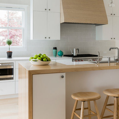Inspiration for a scandinavian light wood floor kitchen remodel in Boston with an undermount sink, flat-panel cabinets, white cabinets, wood countertops and gray backsplash
