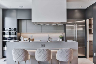 Inspiration for a contemporary gray floor kitchen remodel in Toronto with an undermount sink, flat-panel cabinets, gray cabinets, gray backsplash, stainless steel appliances, an island and gray countertops