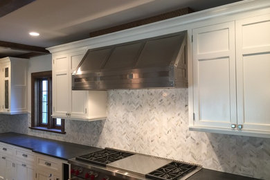 Cette photo montre une cuisine tendance avec des portes de placard blanches, une crédence multicolore, un électroménager en acier inoxydable et îlot.