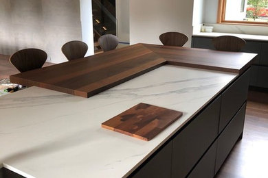 Example of a huge minimalist l-shaped medium tone wood floor and brown floor kitchen design in New York with an undermount sink, flat-panel cabinets, blue cabinets, quartz countertops, multicolored backsplash, stone slab backsplash, colored appliances, an island and multicolored countertops