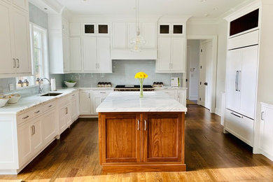 Large dark wood floor and brown floor kitchen pantry photo in New York with a drop-in sink, white cabinets, white backsplash, glass tile backsplash, paneled appliances, an island, white countertops and shaker cabinets