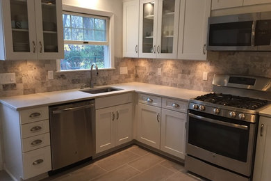 Inspiration for a mid-sized transitional l-shaped porcelain tile eat-in kitchen remodel in New York with an undermount sink, shaker cabinets, white cabinets, quartz countertops, gray backsplash, stone tile backsplash, stainless steel appliances and no island
