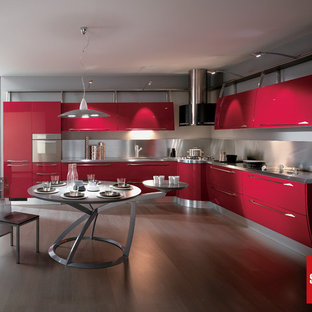 Large modern eat-in kitchen ideas - Eat-in kitchen - large modern l-shaped medium tone wood floor eat-in kitchen idea in Montreal with flat-panel cabinets, red cabinets, stainless steel countertops, metallic backsplash, metal backsplash, stainless steel appliances and a peninsula