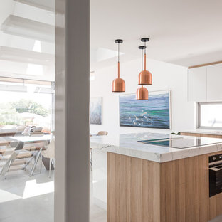 Design ideas for a contemporary l-shaped open plan kitchen in Perth with an undermount sink, light wood cabinets, marble benchtops, black appliances, ceramic floors, with island, grey floor, white benchtop, flat-panel cabinets and window splashback.
