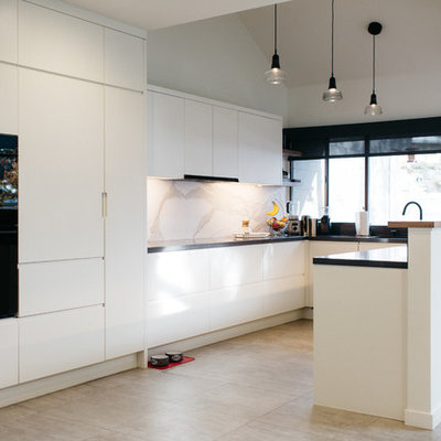 Example of a mid-sized minimalist u-shaped ceramic tile open concept kitchen design in Salt Lake City with flat-panel cabinets, white cabinets, solid surface countertops, white backsplash, stone slab backsplash, black appliances and an island