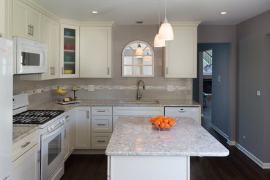 Inspiration for a mid-sized transitional l-shaped vinyl floor and brown floor enclosed kitchen remodel in Chicago with an undermount sink, recessed-panel cabinets, white cabinets, quartz countertops, gray backsplash, ceramic backsplash, white appliances and an island