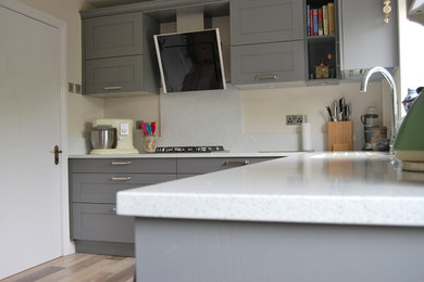 This is an example of a small classic u-shaped kitchen/diner in Cheshire with grey cabinets, quartz worktops, no island, shaker cabinets, white splashback and stone slab splashback.