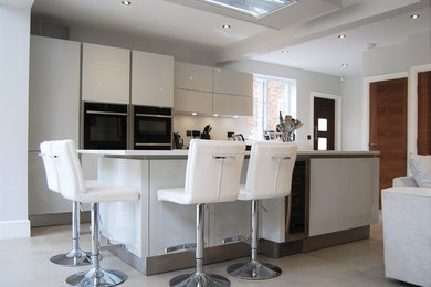 Ejemplo de cocina lineal actual grande abierta con encimera de cuarcita, una isla, armarios con paneles lisos y puertas de armario grises