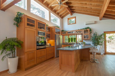 Inspiration pour une cuisine américaine design en L et bois brun de taille moyenne avec un évier encastré, un placard à porte shaker, un plan de travail en stéatite, un électroménager en acier inoxydable, parquet clair, îlot et un sol marron.