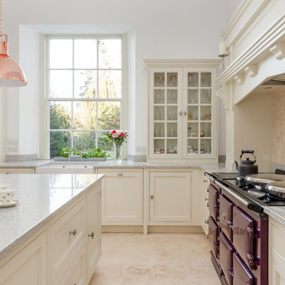 Eat-in kitchen - large traditional l-shaped limestone floor and beige floor eat-in kitchen idea in London with a farmhouse sink, shaker cabinets, white cabinets, granite countertops, beige backsplash, limestone backsplash, colored appliances, an island and gray countertops