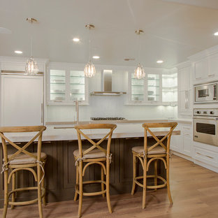 Photo of a large transitional l-shaped separate kitchen in Phoenix with recessed-panel cabinets, white cabinets, with island, an undermount sink, limestone benchtops, grey splashback, mosaic tile splashback, panelled appliances, light hardwood floors and brown floor.