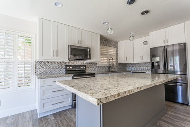 Example of a mid-sized transitional l-shaped porcelain tile and brown floor kitchen design in Phoenix with an undermount sink, shaker cabinets, white cabinets, granite countertops, multicolored backsplash, porcelain backsplash, stainless steel appliances, an island and beige countertops