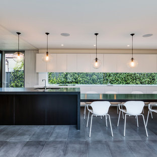 Imagen de cocina comedor de galera y blanca y negra, actual, con fregadero bajoencimera, armarios con paneles lisos, encimera de madera, una isla, salpicadero de vidrio templado, electrodomésticos de acero inoxidable, suelo de baldosas de cerámica y suelo negro