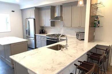 Example of a mid-sized trendy l-shaped dark wood floor eat-in kitchen design in New York with an undermount sink, shaker cabinets, gray cabinets, marble countertops, white backsplash, stone tile backsplash, stainless steel appliances and an island