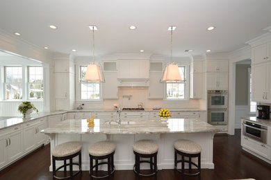 Large elegant u-shaped eat-in kitchen photo in New York with an undermount sink, recessed-panel cabinets, white cabinets, granite countertops, white backsplash, subway tile backsplash, stainless steel appliances and an island
