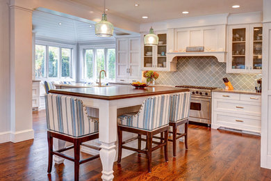 Example of a mid-sized beach style l-shaped medium tone wood floor eat-in kitchen design in New York with an undermount sink, white cabinets, gray backsplash, stainless steel appliances, shaker cabinets, granite countertops, ceramic backsplash and an island