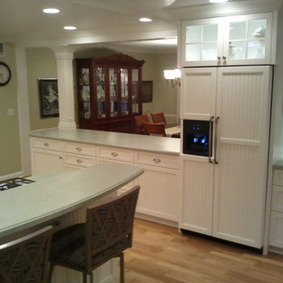 Large coastal eat-in kitchen appliance - Example of a large beach style u-shaped light wood floor eat-in kitchen design in Other with an integrated sink, flat-panel cabinets, white cabinets, solid surface countertops, white backsplash, ceramic backsplash, stainless steel appliances and a peninsula