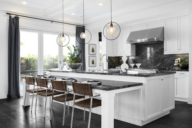 Classic galley kitchen/diner in San Diego with shaker cabinets, black splashback, stainless steel appliances, an island, black floors and black worktops.