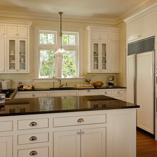 Small beach style u-shaped open plan kitchen in Seattle with an undermount sink, beaded inset cabinets, white cabinets, granite benchtops, yellow splashback, ceramic splashback, panelled appliances, medium hardwood floors and no island.