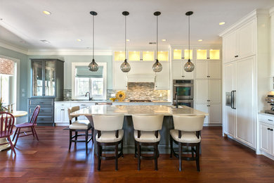 Inspiration for a mid-sized transitional single-wall dark wood floor open concept kitchen remodel in Charleston with a double-bowl sink, raised-panel cabinets, white cabinets, quartz countertops, multicolored backsplash, glass sheet backsplash, paneled appliances and an island