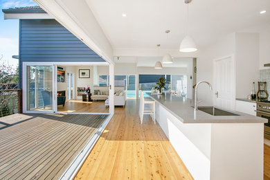 This is an example of a large nautical open plan kitchen in Wollongong with white cabinets, engineered stone countertops, blue splashback, ceramic splashback, an island and grey worktops.