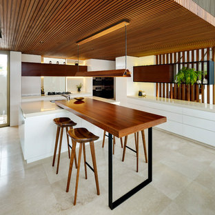 This is an example of a contemporary l-shaped kitchen in Sydney with flat-panel cabinets, white cabinets, multiple islands, beige floor and beige benchtop.