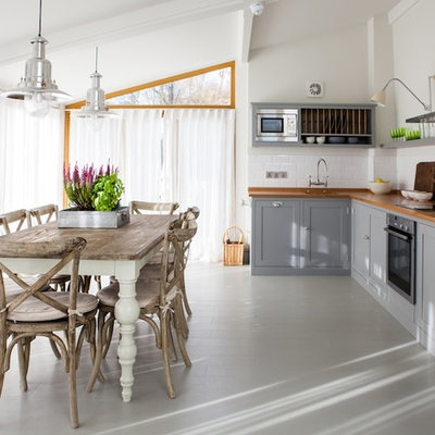 Cottage painted wood floor eat-in kitchen photo in Kent with shaker cabinets, gray cabinets, wood countertops, white backsplash, ceramic backsplash, stainless steel appliances, a farmhouse sink and no island