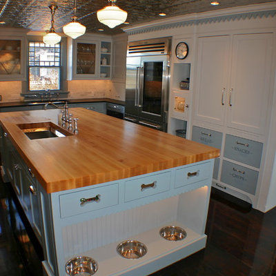 Elegant kitchen photo in Boston with an undermount sink, shaker cabinets, white cabinets, wood countertops, stainless steel appliances and brown countertops