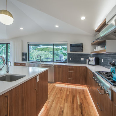 Eat-in kitchen - mid-century modern light wood floor eat-in kitchen idea in Seattle with a single-bowl sink, flat-panel cabinets, dark wood cabinets, blue backsplash, glass tile backsplash, stainless steel appliances and white countertops