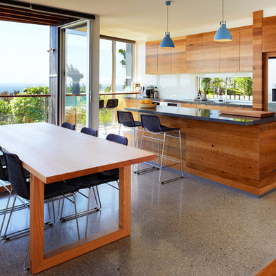 Example of a mid-sized trendy galley concrete floor eat-in kitchen design in Sydney with flat-panel cabinets, medium tone wood cabinets, quartz countertops, white backsplash, glass sheet backsplash, stainless steel appliances and an island