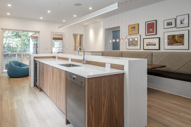 Trendy galley light wood floor and beige floor eat-in kitchen photo in Ottawa with an undermount sink, flat-panel cabinets, medium tone wood cabinets, stainless steel appliances, an island and white countertops